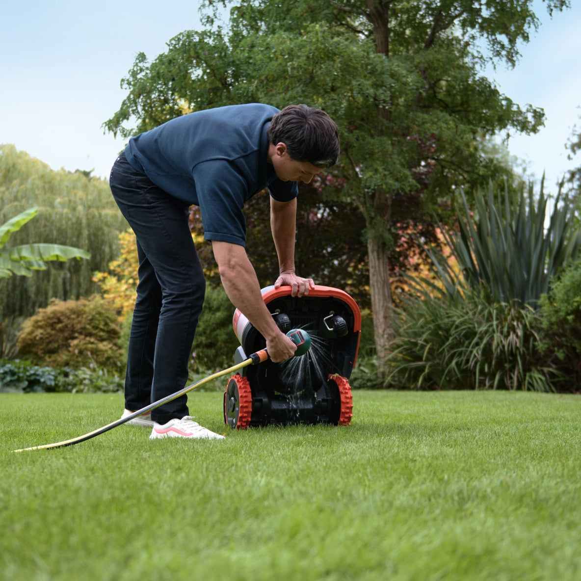 Segway Navimow H2 robot lawn mower tilted while rinsed with hose outside