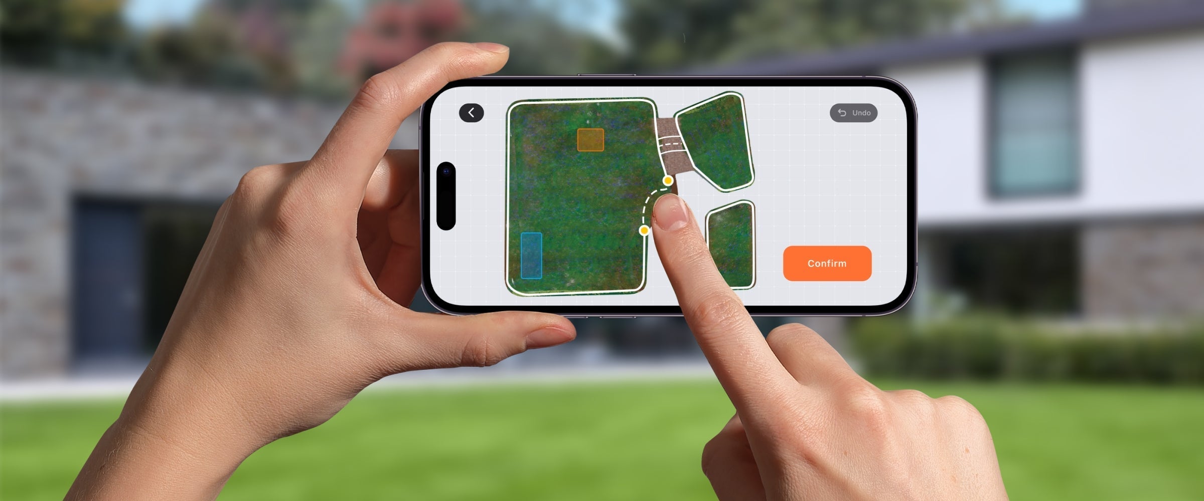 Hands hold phone running Segway Navimow H2 lawn zoning UI with dotted link and orange Confirm