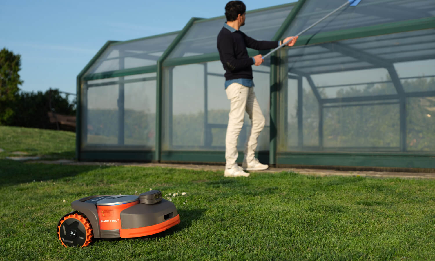 Navimow i110N robot lawn mower works while a man cleans.