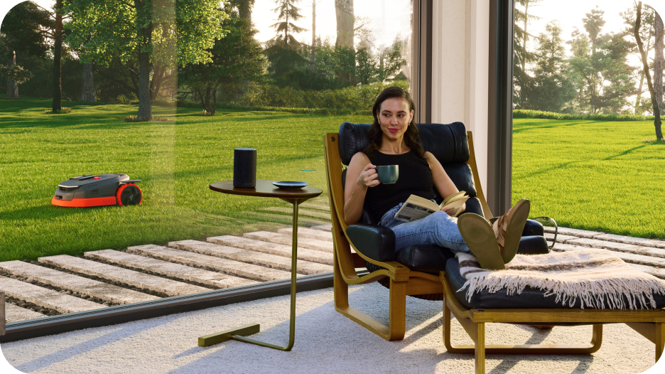 Navimow i105E robot lawn mower mows while a woman relaxes.