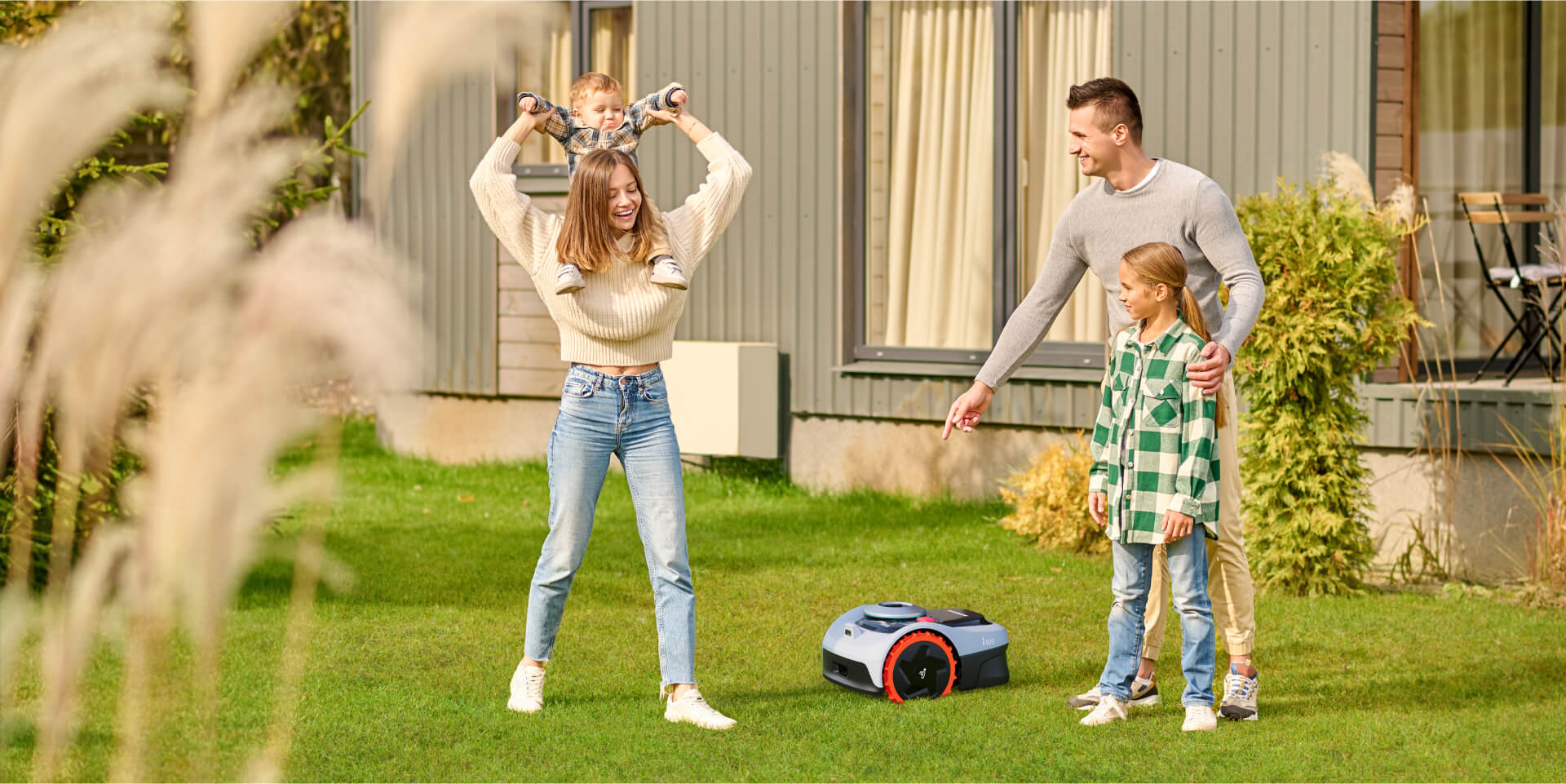 A happy family watching a Navimow i105 robot lawn mower.