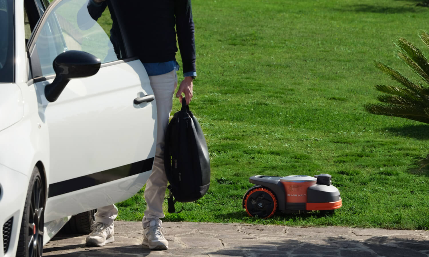 Navimow i110E robot lawn mower beside car on green grass.