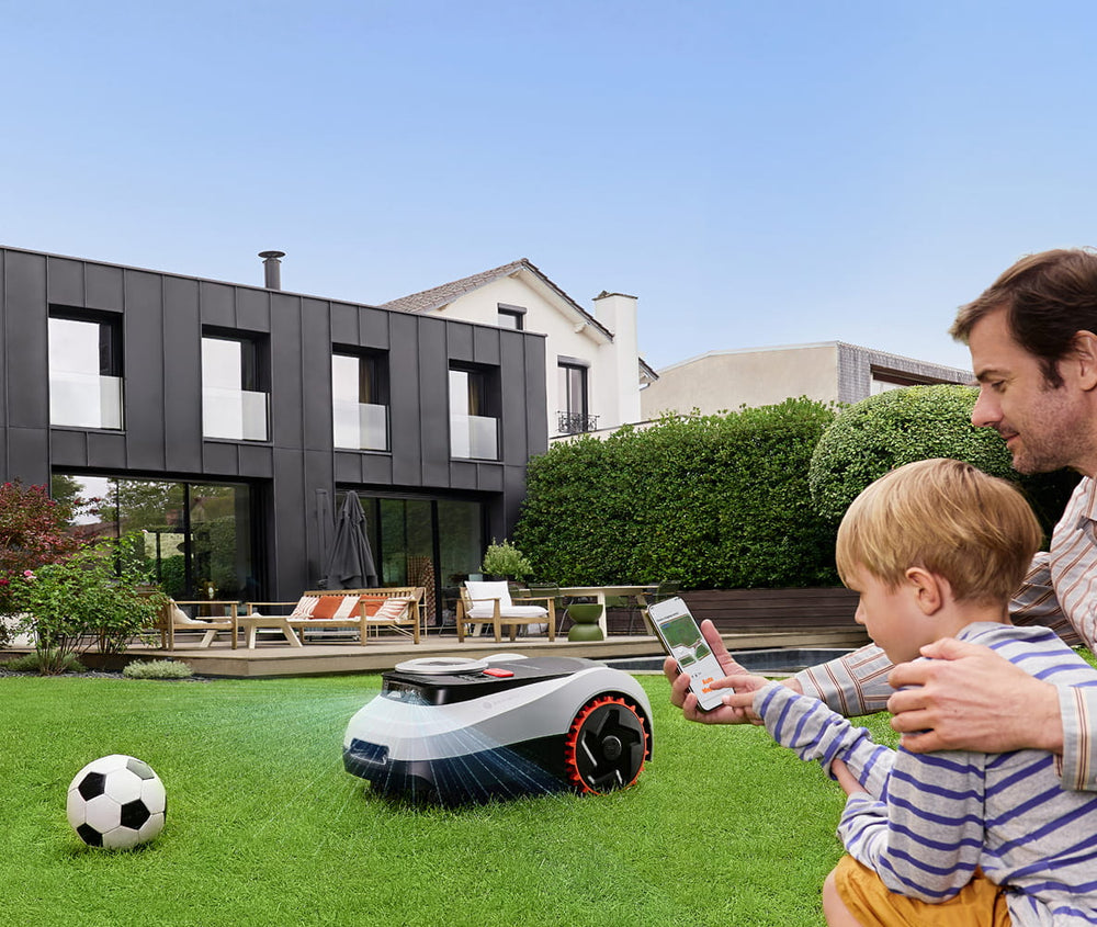 Father and son watch Navimow i110E robot lawn mower working.